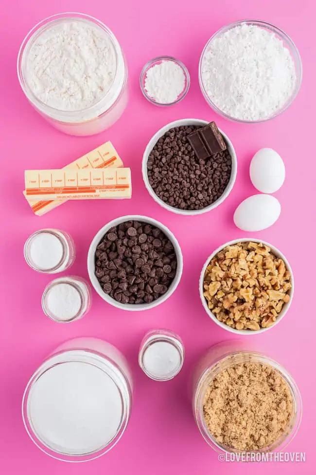ingredients to make chocolate chip cookies on a pink background
