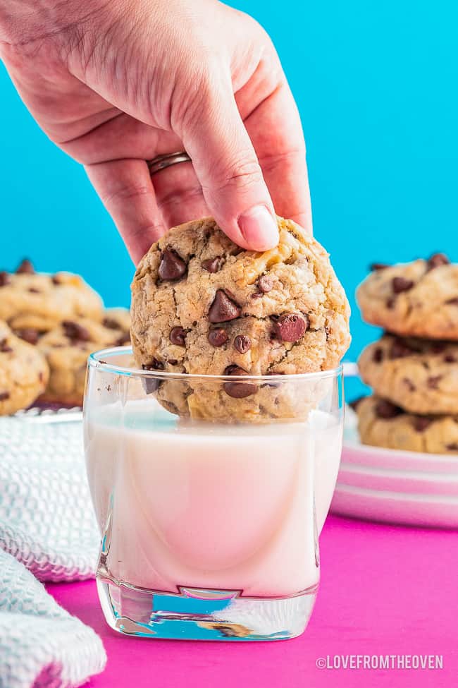 a chocolate chip cookie being dipped in a glass of milk