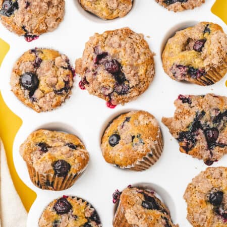 A white muffin pan holding blueberry banana muffins