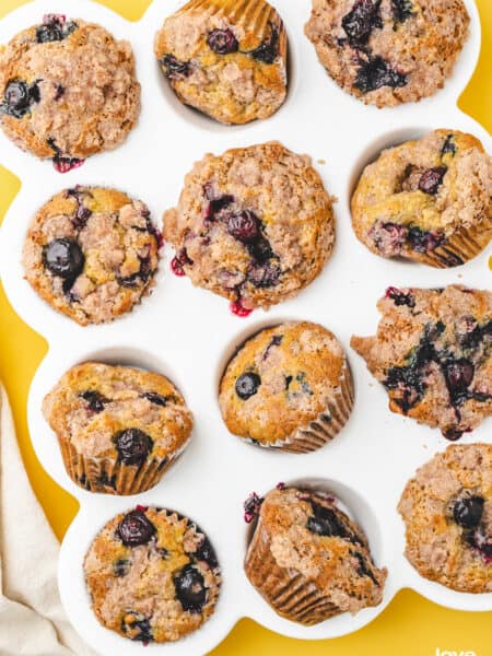 A white muffin pan holding blueberry banana muffins