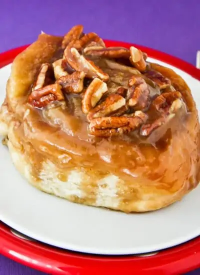 A caramel roll with pecans on top.