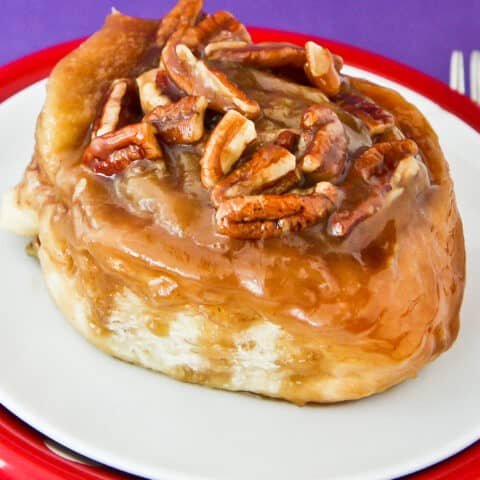 A caramel roll with pecans on top.