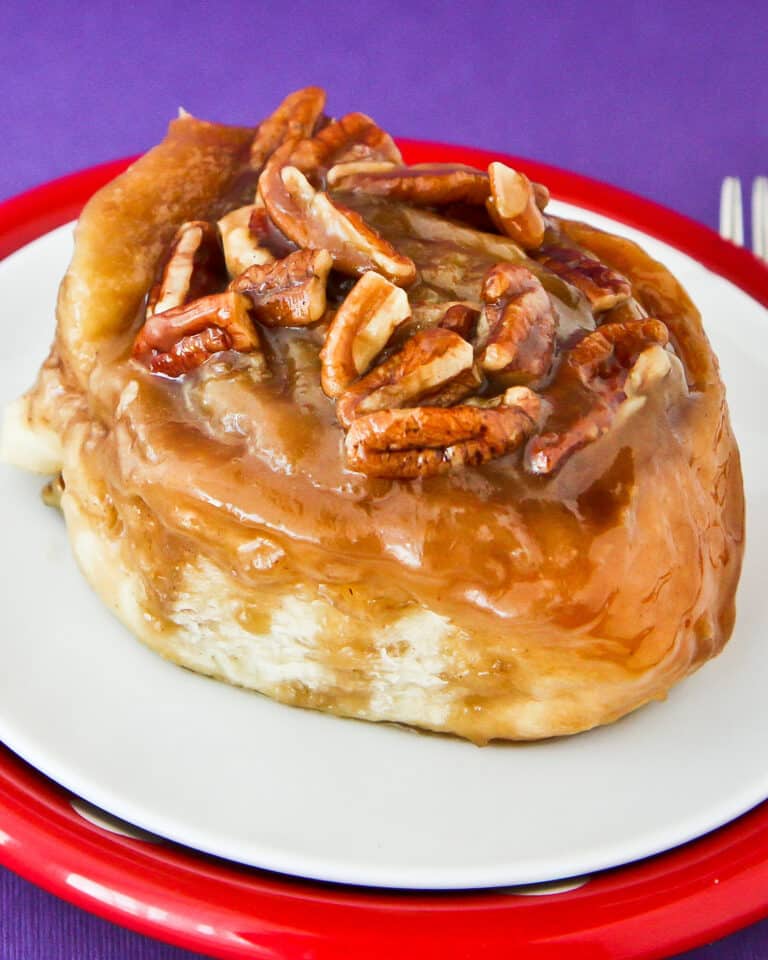 A caramel roll with pecans on top.
