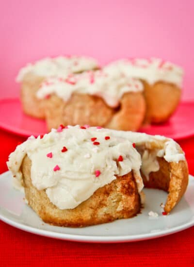 A whole wheat cinnamon roll with frosting and sprinkles.