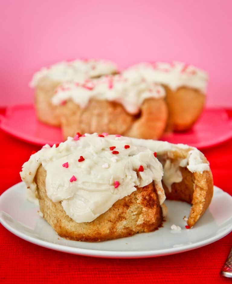 A whole wheat cinnamon roll with frosting and sprinkles.