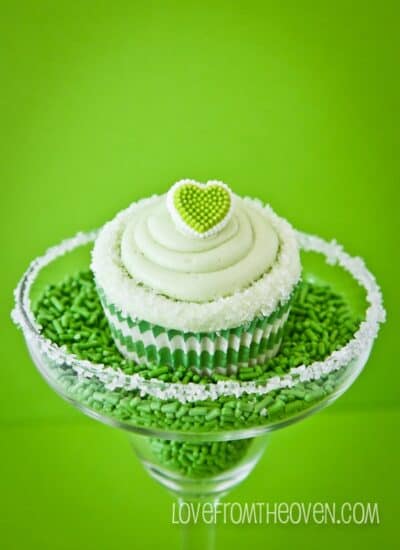 A green cupcake in a margarita glass full of sprinkles