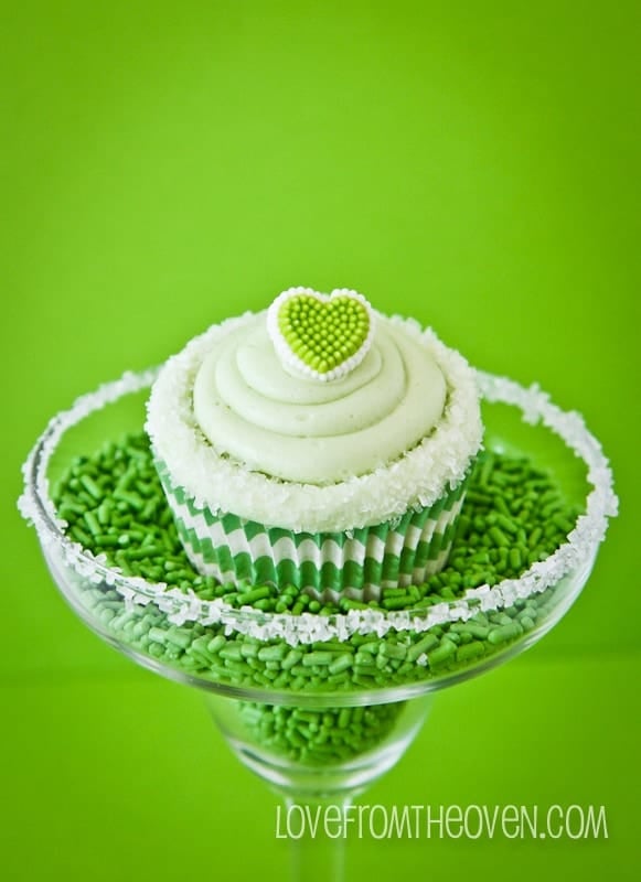 A green cupcake in a margarita glass full of sprinkles