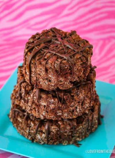 Chocolate rice krispie treats on a blue plate on a pink background.