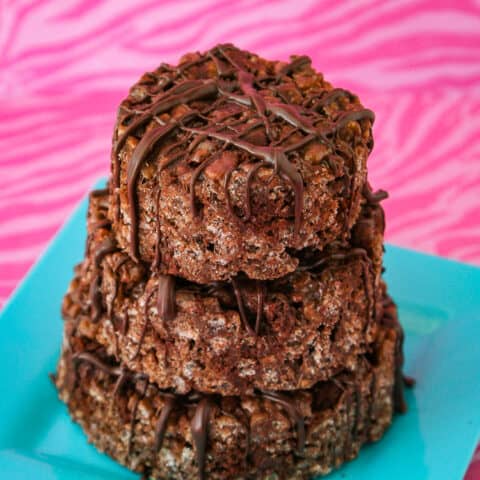 Chocolate rice krispie treats on a blue plate on a pink background.