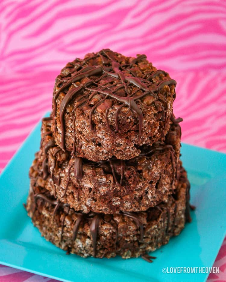 Chocolate rice krispie treats on a blue plate on a pink background.