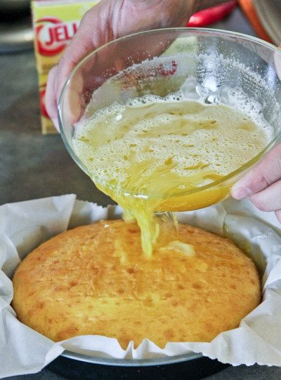 Pouring lemon Jello onto Lemon Poke Cake
