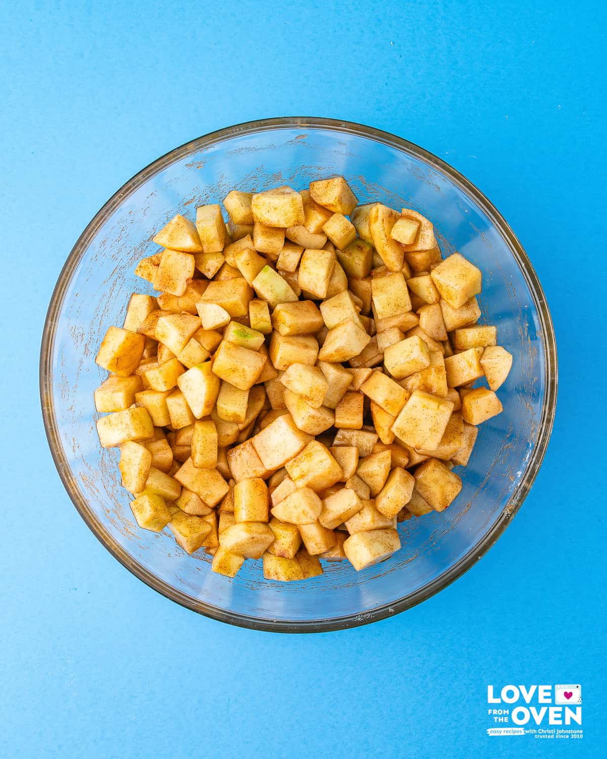 a bowl of sliced and diced apples coated in a cinnamon sugar mixture