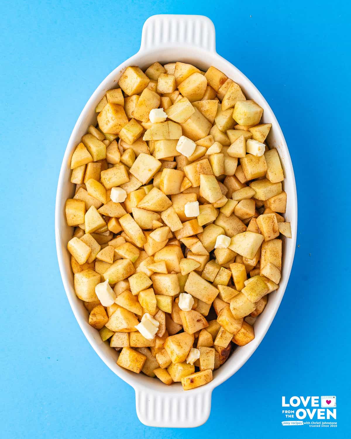a baking dish of the cinnamon coated apples and cubed butter