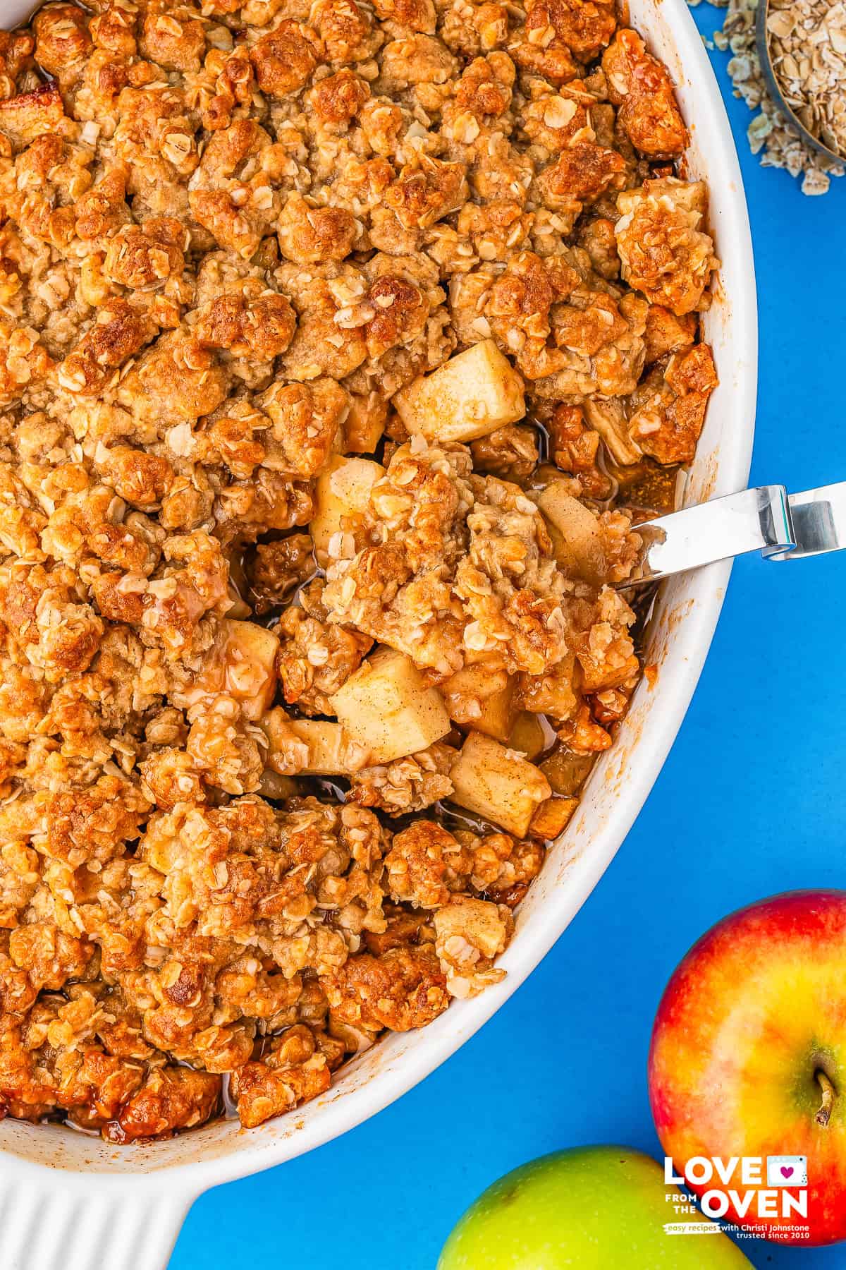apple crumble in a baking dish with a spoon taking a serving out of it.