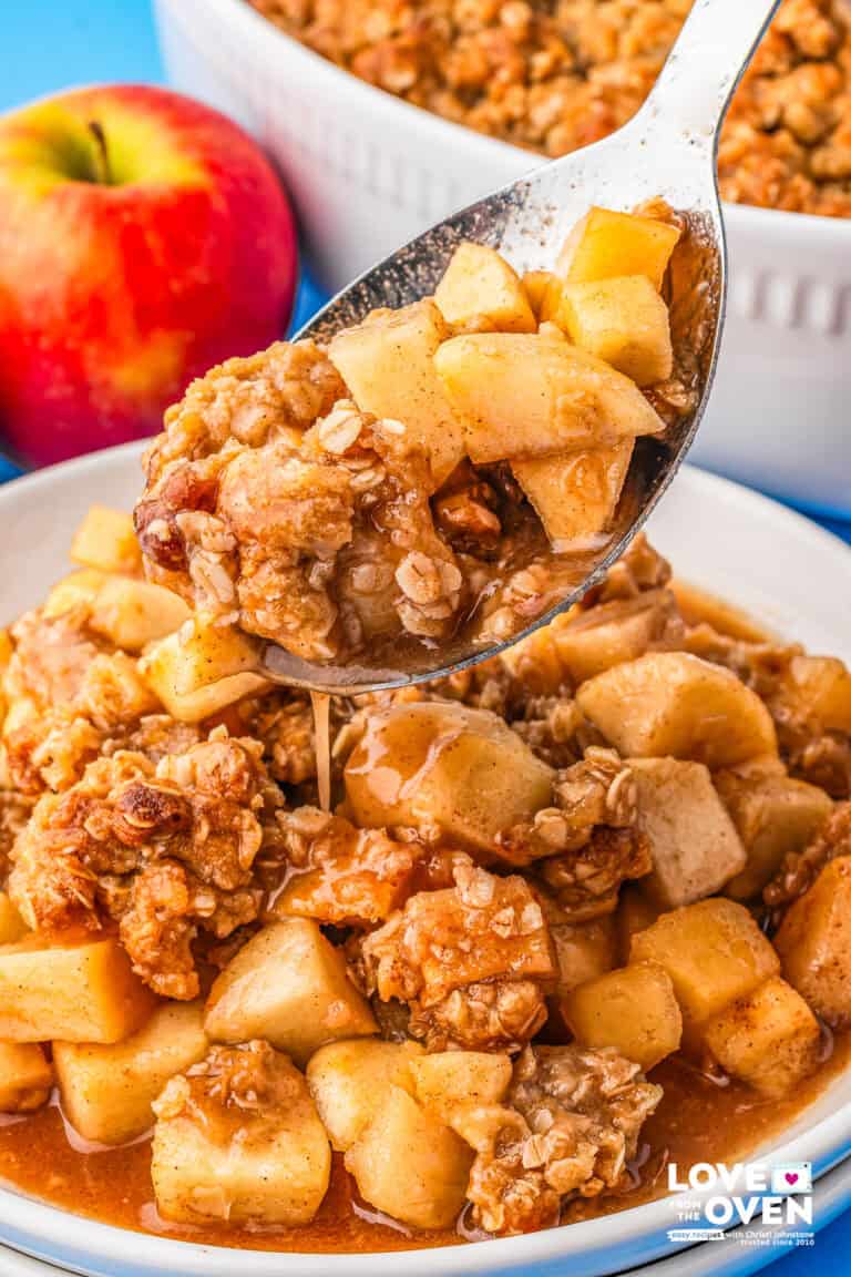 A spoon taking a serving of apple crumble from a plate