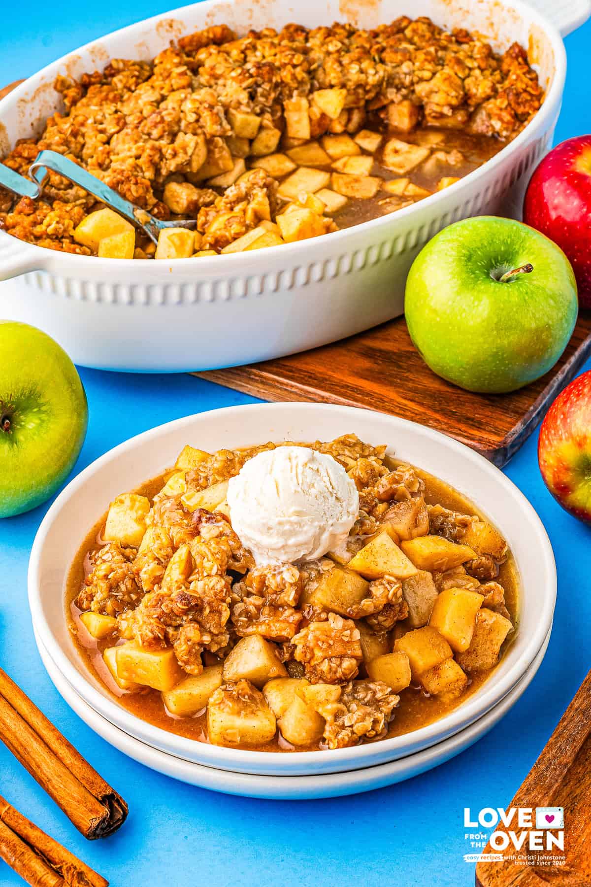 a plate of apple crumble with the baking dish of apple crumble in the background