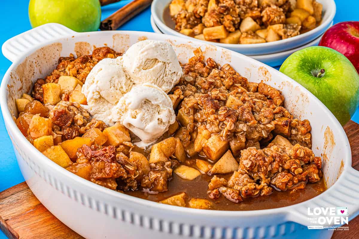 a baking dish of apple crumble with scoops of vanilla ice cream on top