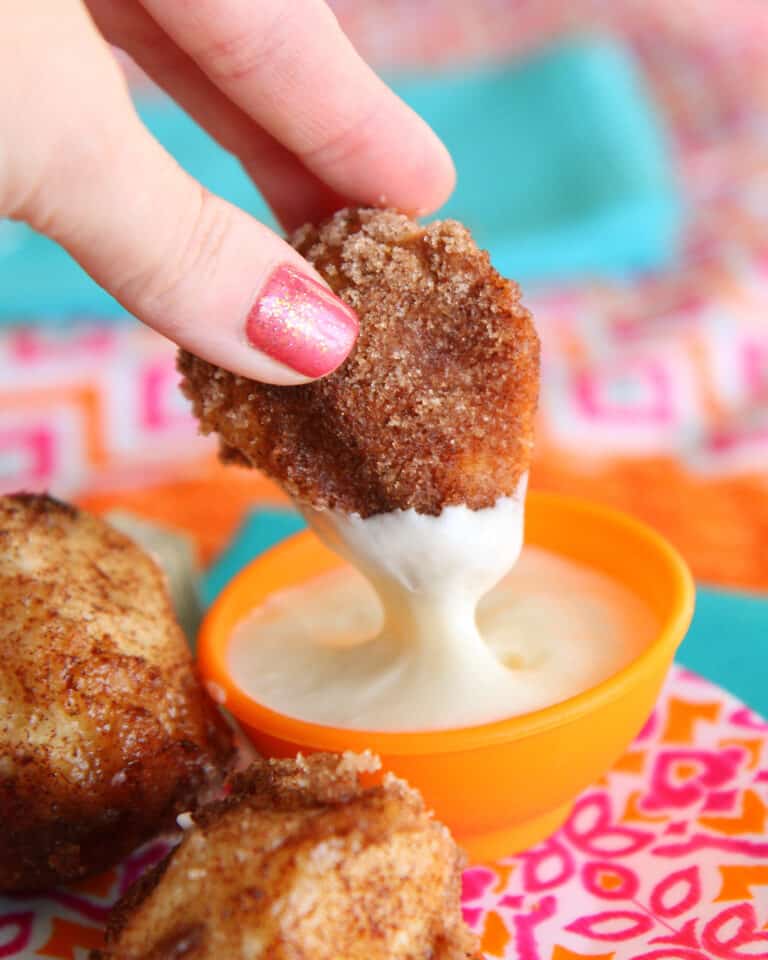 A piece of pull apart bread being dipped in frosting.