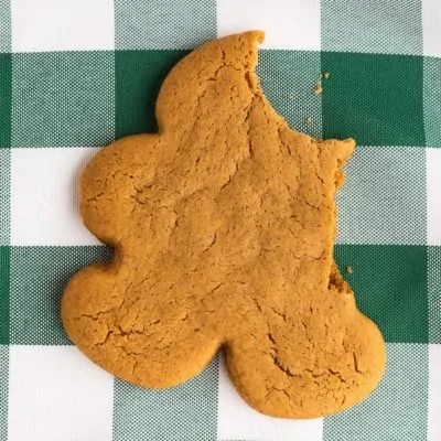 A gingerbread man with a bite taken out on a green and white napkin