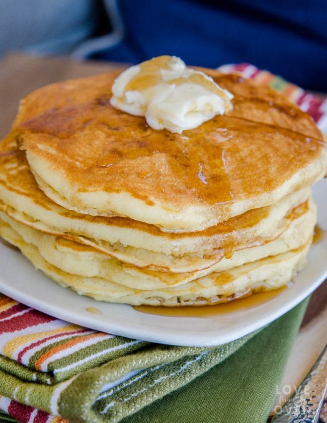 A stack of fluffy pancakes topped with butter and syrup