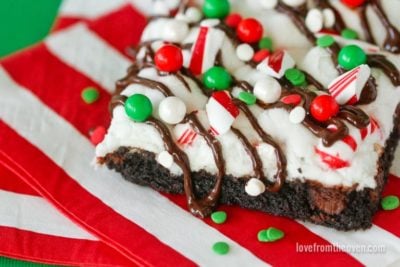A peppermint brownie bar covered in sprinkles and crushed candy canes on a red and white napkin