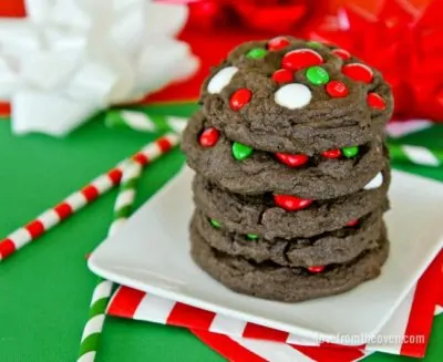 Five Christmas M&M cookies stacked on a white plate