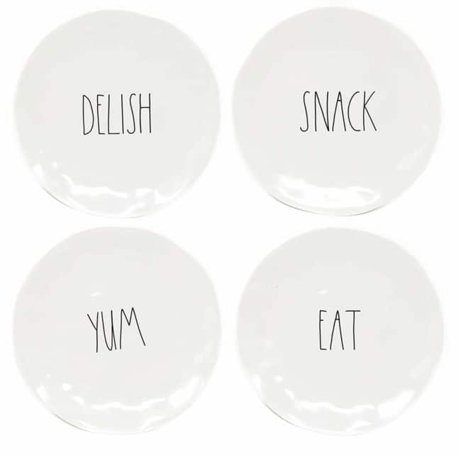 Four Rae Dunn plates with the words delish, snack, yum and eat written on them