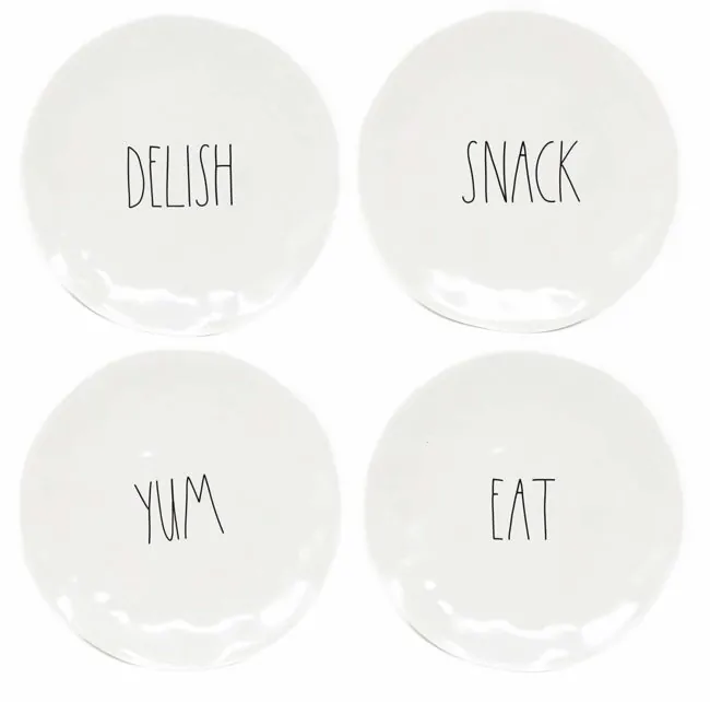 Four Rae Dunn plates with the words delish, snack, yum and eat written on them