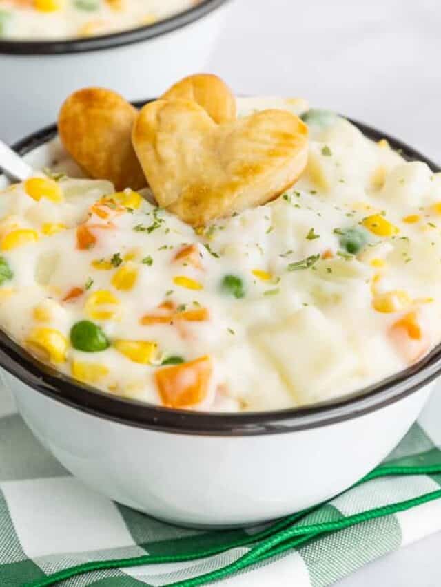 a bowl of pot pie soup with two heart crackers on top