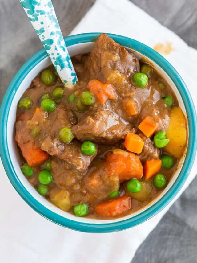 Beef stew with peas and carrots in a bowl with a spoon