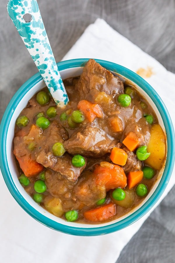 Beef stew with peas and carrots in a bowl with a spoon