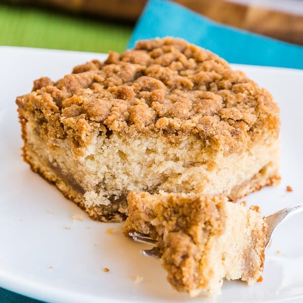 Piece of crumb cake with a bite taken out on a white plate 