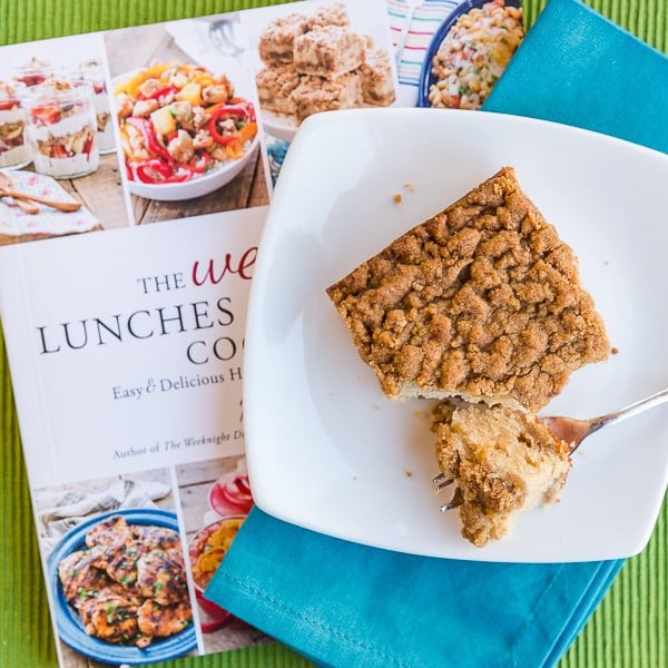 Piece of crumb cake on a plate sitting on a cookbook