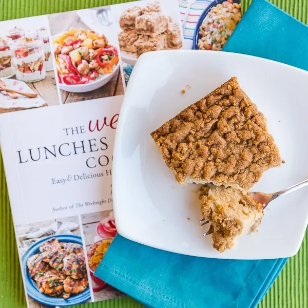 Piece of crumb cake on a plate sitting on a cookbook
