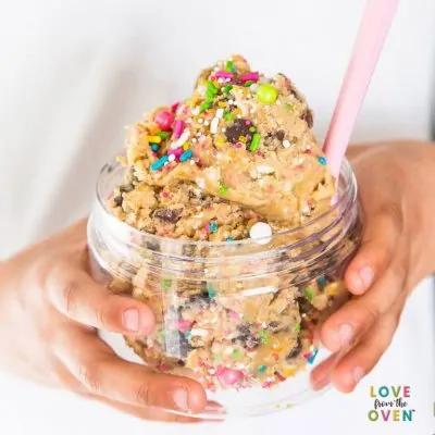 Cookie dough in a clear bowl with sprinkles and a pink spoon