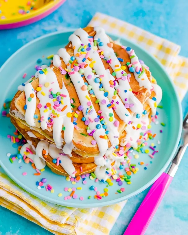 Blue plate with french toast on it topped with frosting and sprinkles