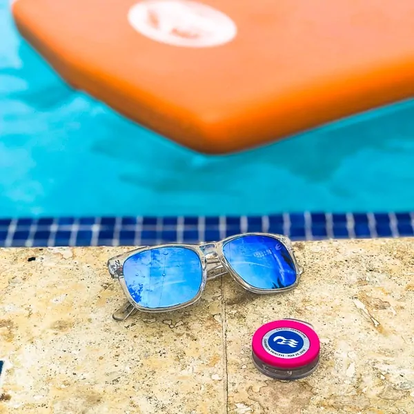 Sunglasses and ocean medallion next to a pool with an orange pool float