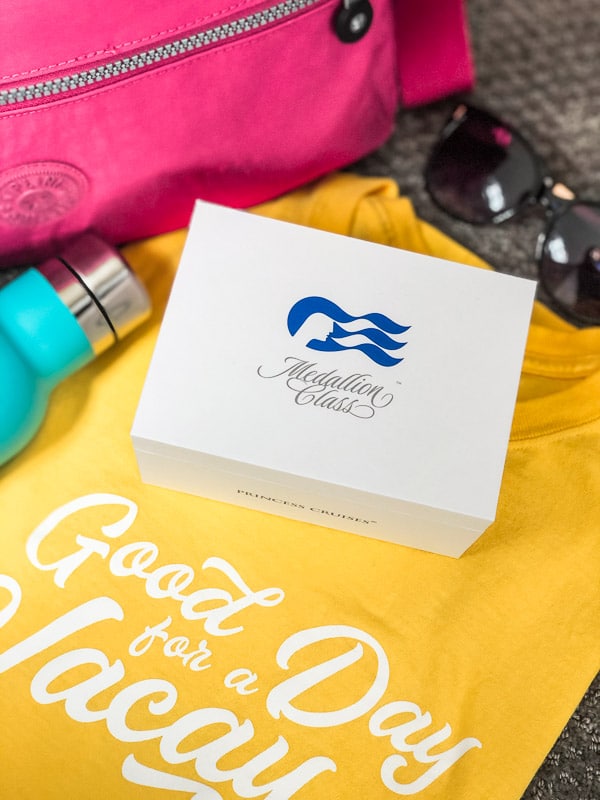 Ocean Medallion box on a yellow shirt next to a pink bag and sunglasses