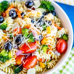 Bowl of pasta salad with tomatoes, olives, broccoli, carrots and cheese