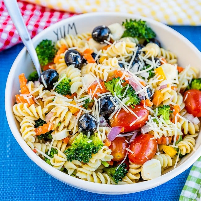 White bowl with pasta salad inside it, sitting on a blue placemat