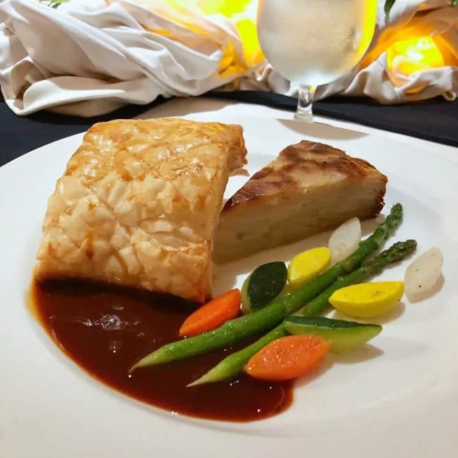 A plate with vegetables and beef wellington at a chef's table dinner on a Princess Cruise