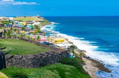 Coast view in Old San Juan Puerto Rico with green mountains, blue water and colorful houses