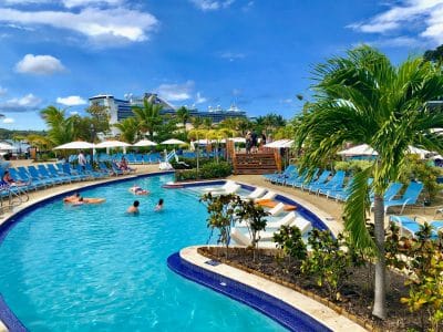 Blue swimming pool at a resort in Grand Turk with green trees and a Princess cruise ship in the background