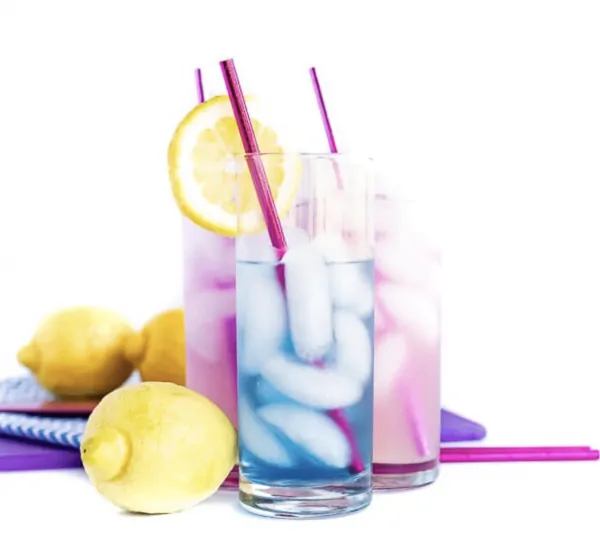 Blue cocktail in front of purple cocktails with lemons