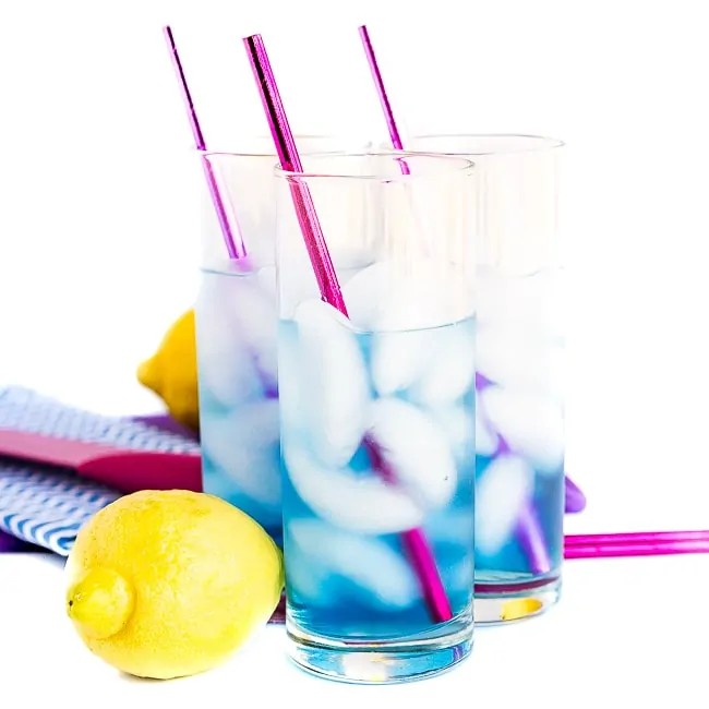 Three blue cocktails with pink straws and lemons