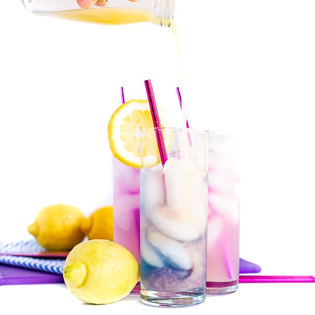 Lemon juice being poured into a cocktail making it change colors