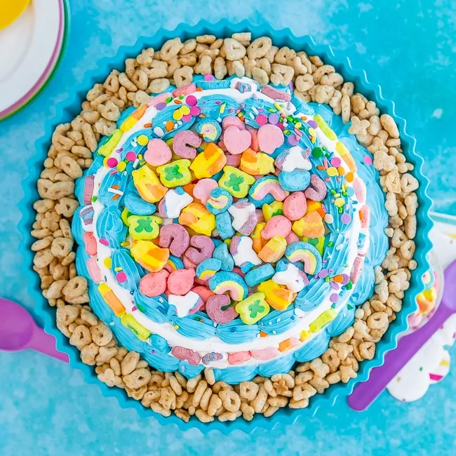 Lucky charms cereal on top of an ice cream cake on a blue background