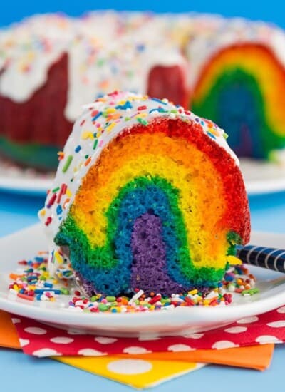 A slice of rainbow bundt cake on a white plate