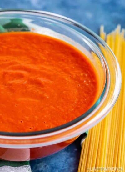 a bowl of tomato sauce next to uncooked spaghetti
