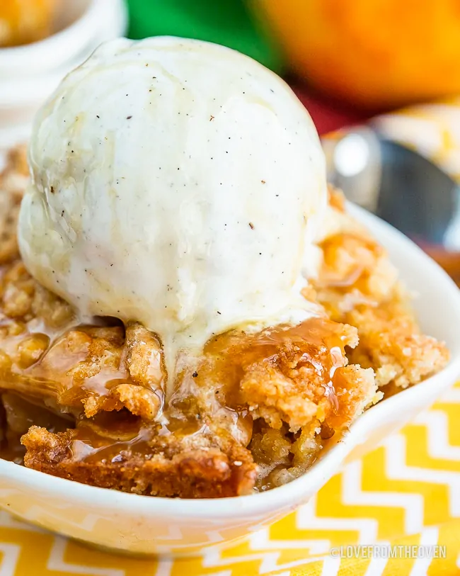 Bowl of easy apple cobbler with vanilla ice cream on top, sitting on a yellow and white napkin